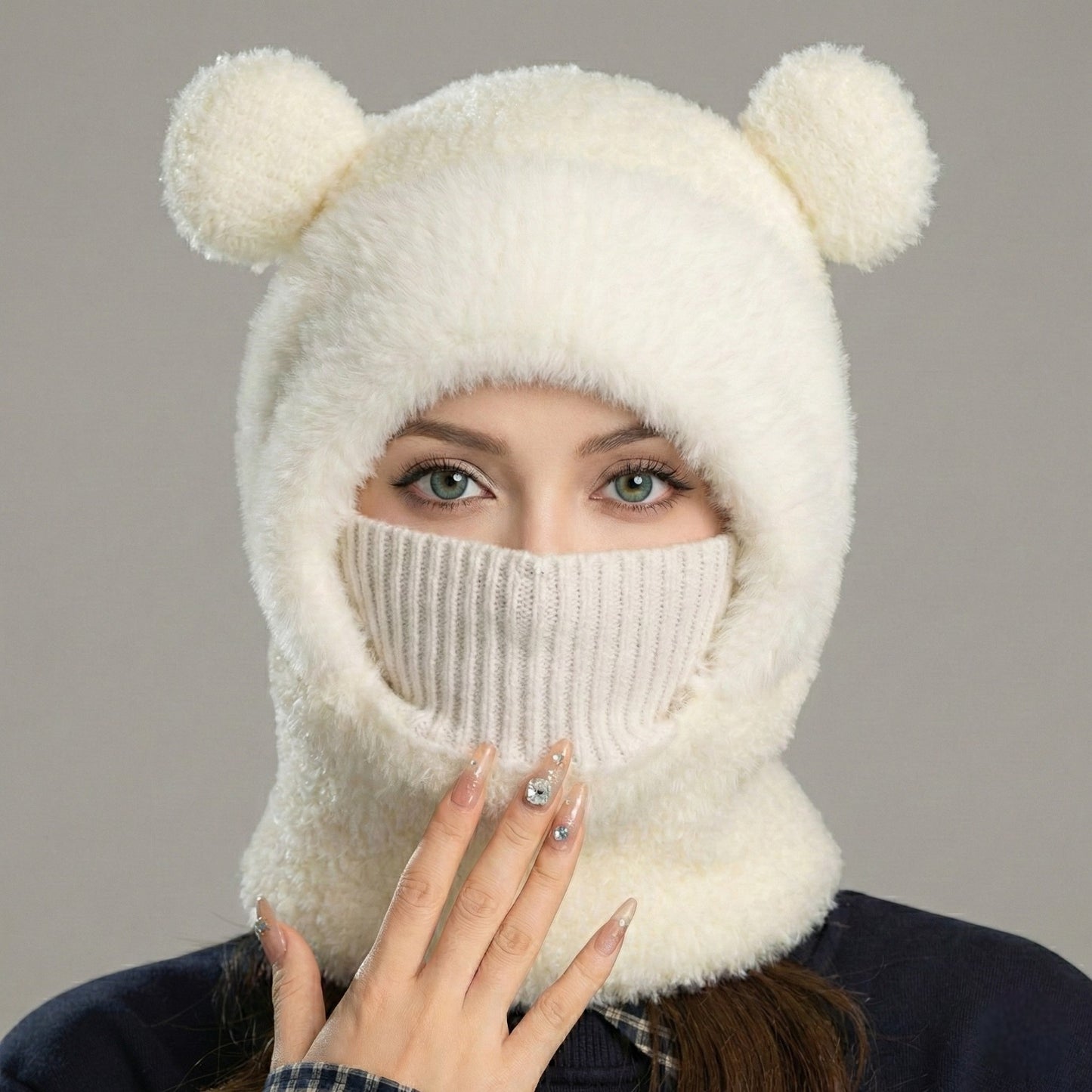 Woman wearing a white knitted balaclava with bear ears on a gray background