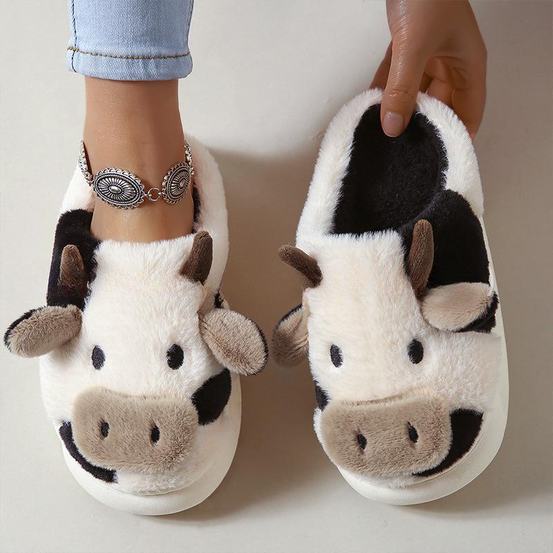 Cow-themed slippers worn by a person on a neutral background