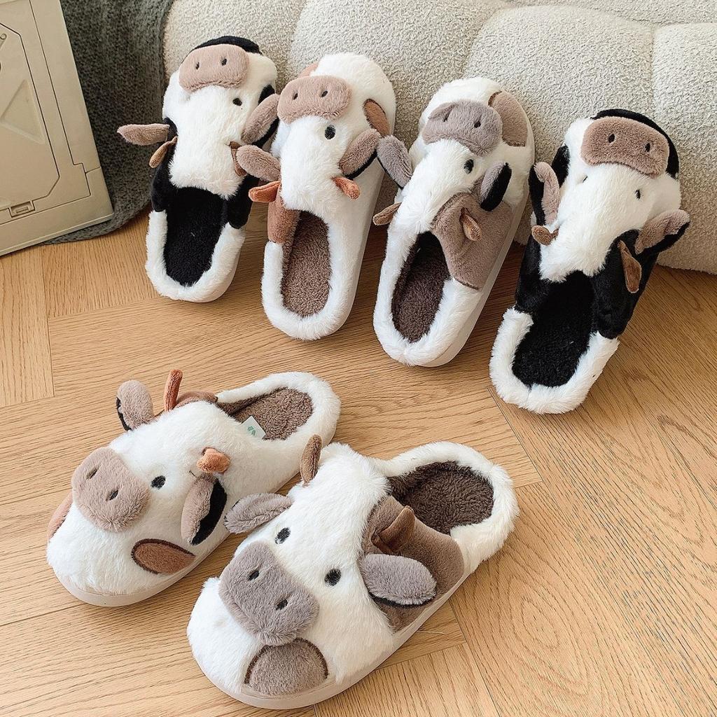 Set of cow-themed slippers on a wooden floor with a neutral background