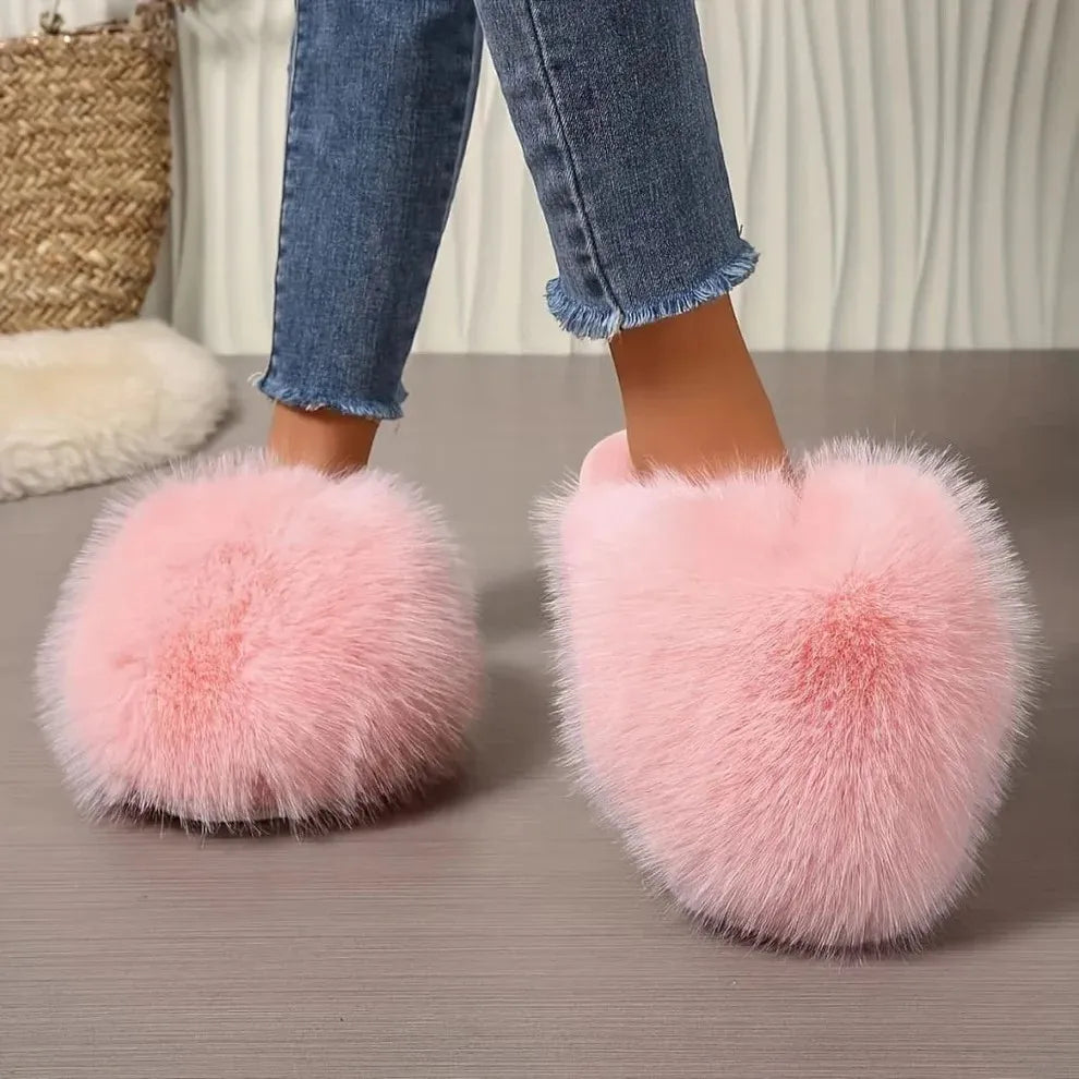 Pink fluffy slippers worn with blue jeans on a neutral background