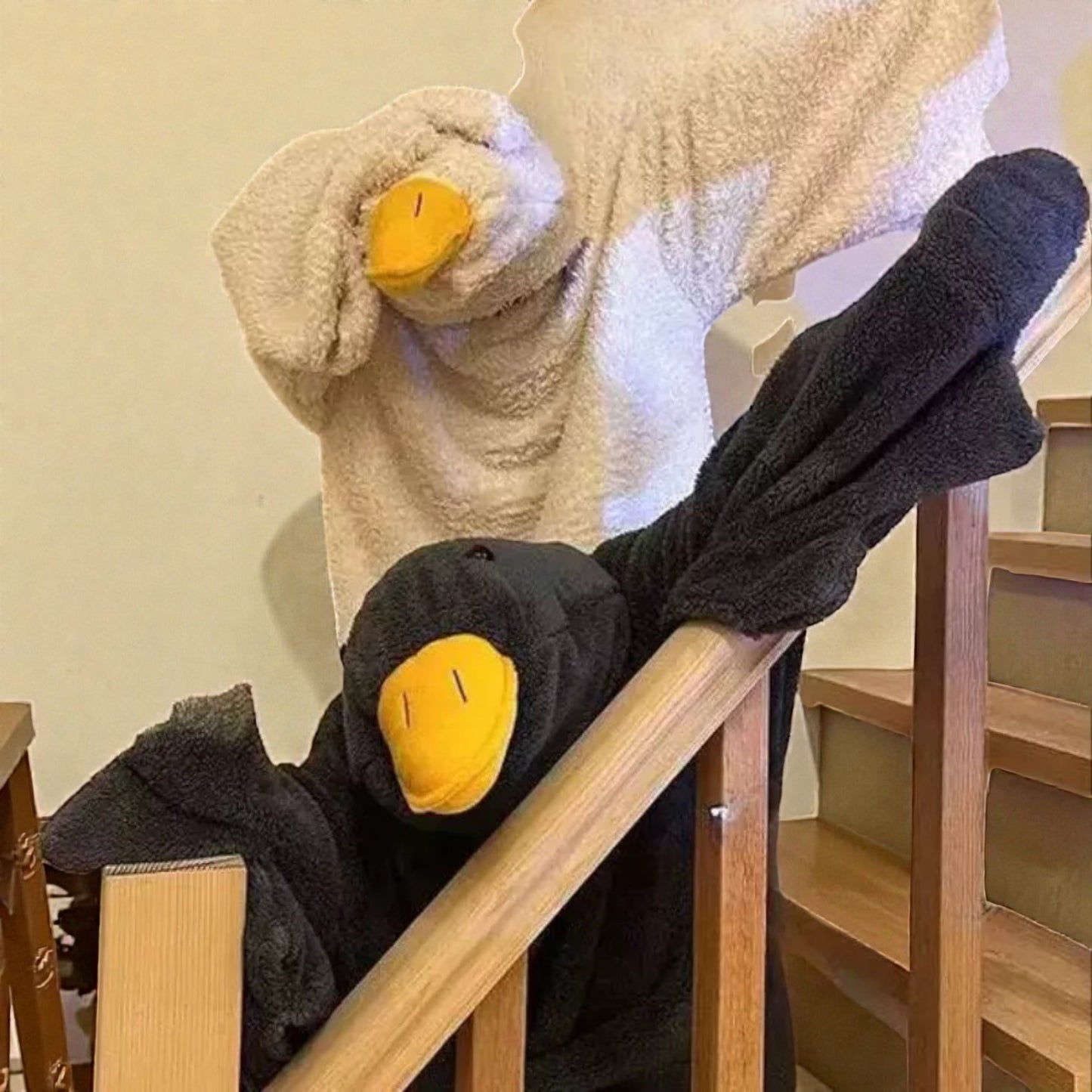 Two plush duck toys on a wooden staircase.