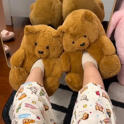 A person wearing white socks and patterned pajama pants sits on a black-and-white rug, holding two large brown teddy bear plush toys in front of their legs.
