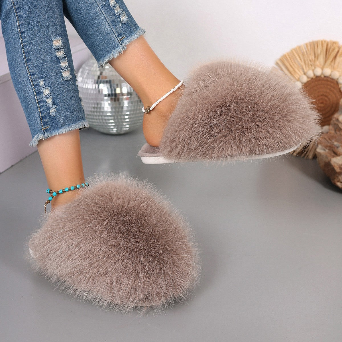 Fuzzy slippers worn with denim jeans on a neutral background
