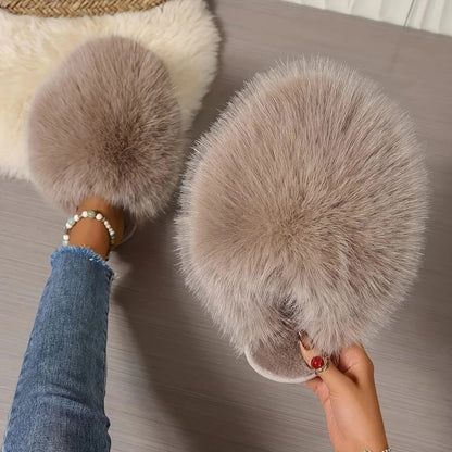 Furry slippers being worn with a person's foot visible, on a neutral background.