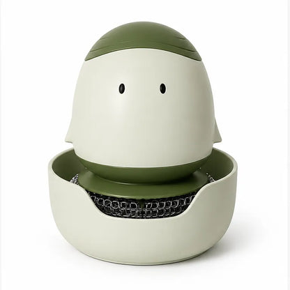 A ceramic dishwashing sponge holder with a minimalist face design, featuring a light cream-colored body, an olive green top dome, and a black wire sponge resting inside the mouth, set against a plain white background.