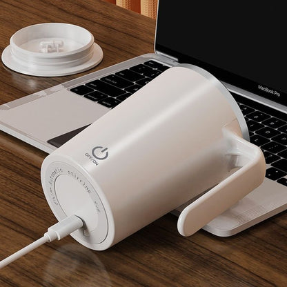 White mug with power symbol on a wooden desk next to a laptop