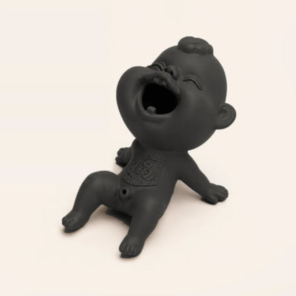 A matte black ceramic laughing baby figurine sitting on a light beige background.
