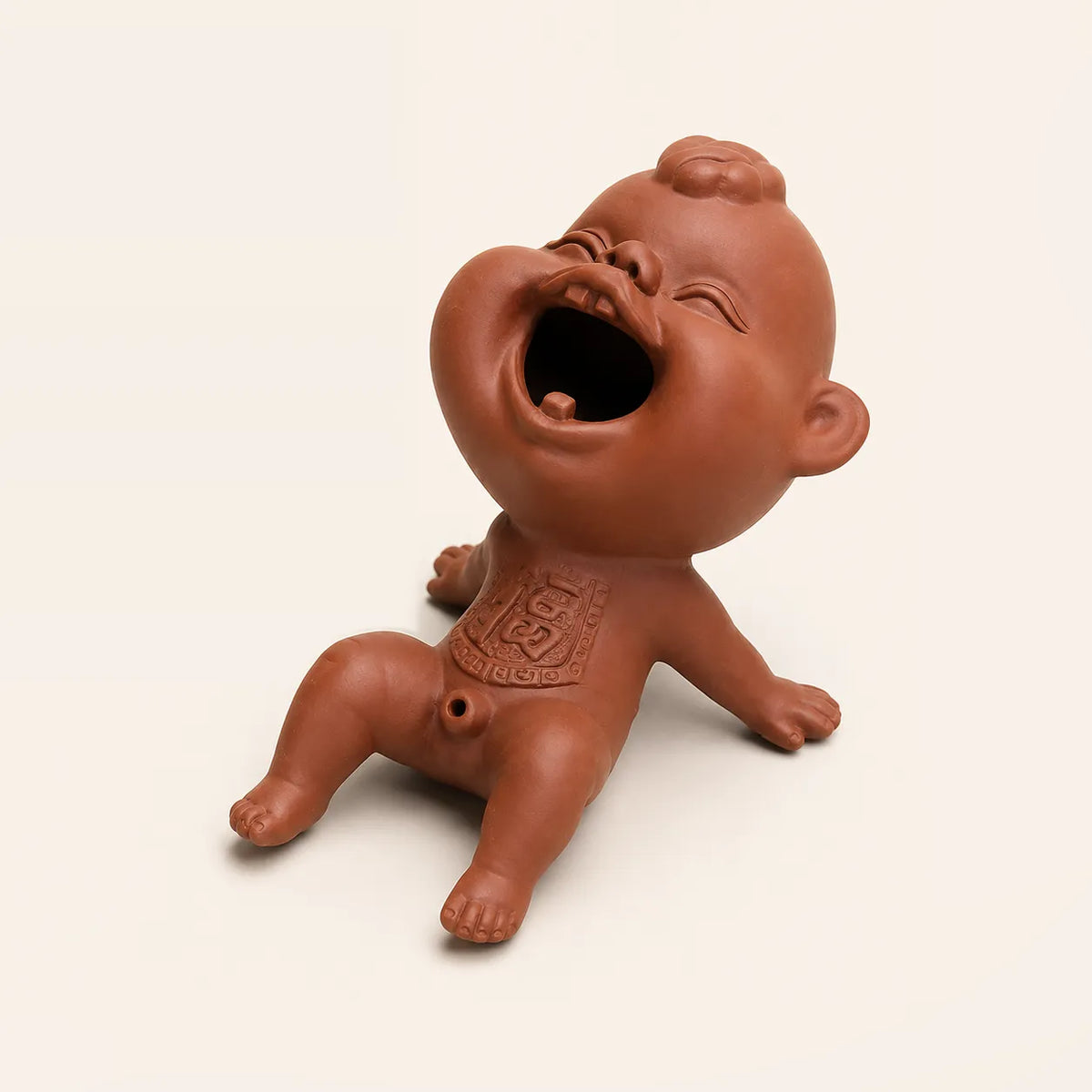 A terracotta-colored ceramic laughing baby figurine sitting on a plain off-white background.