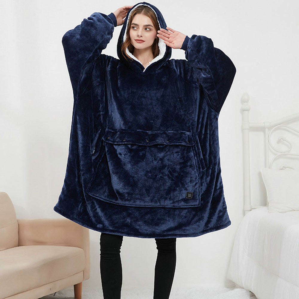 Person wearing a navy blue fleece poncho in a room with white walls and a beige chair.