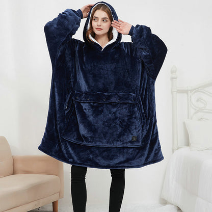 Person wearing a navy blue fleece poncho in a room with white walls and a beige chair.