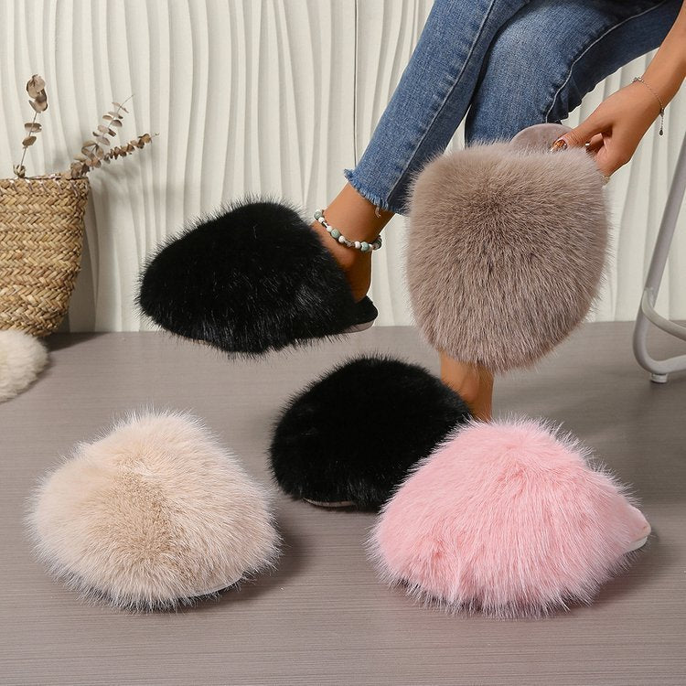 Fluffy slippers in black, beige, and pink on a surface with a person wearing them.