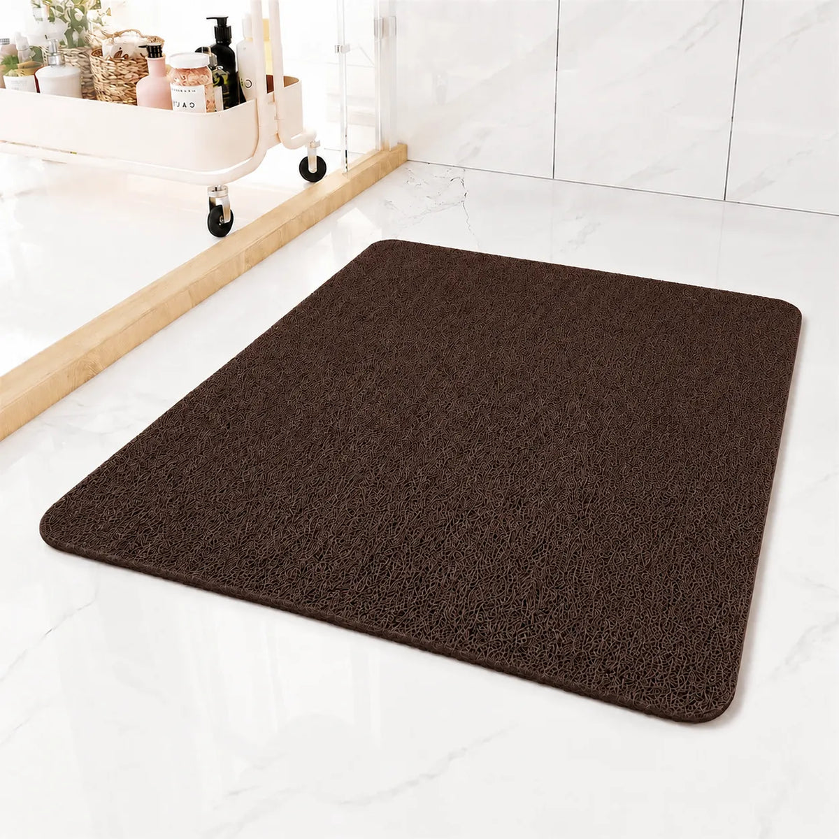 A dark brown rectangular bath mat with rounded corners, shown on a white marble-look floor in a bathroom setting.
