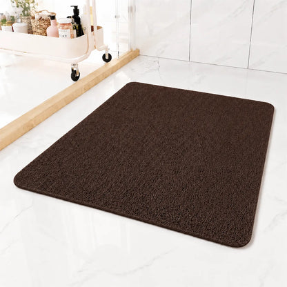 A dark brown rectangular bath mat with rounded corners, shown on a white marble-look floor in a bathroom setting.