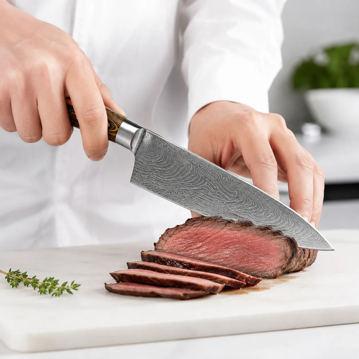 A close-up of a chef slicing a cooked steak with a large Damascus steel kitchen knife on a white cutting board.
