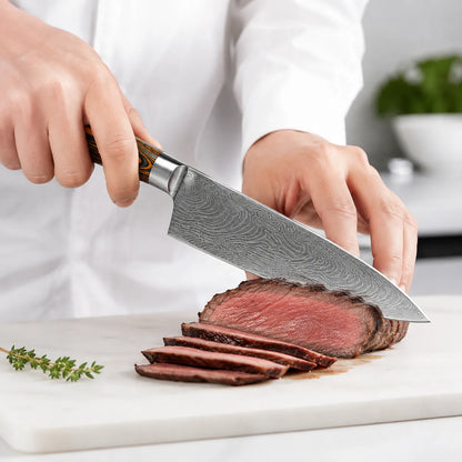 A close-up of a chef slicing a cooked steak with a large Damascus steel kitchen knife on a white cutting board.