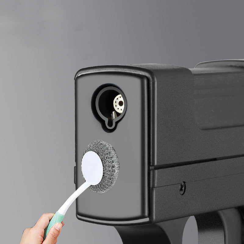 Person cleaning a black appliance with a scrubber against a gray background