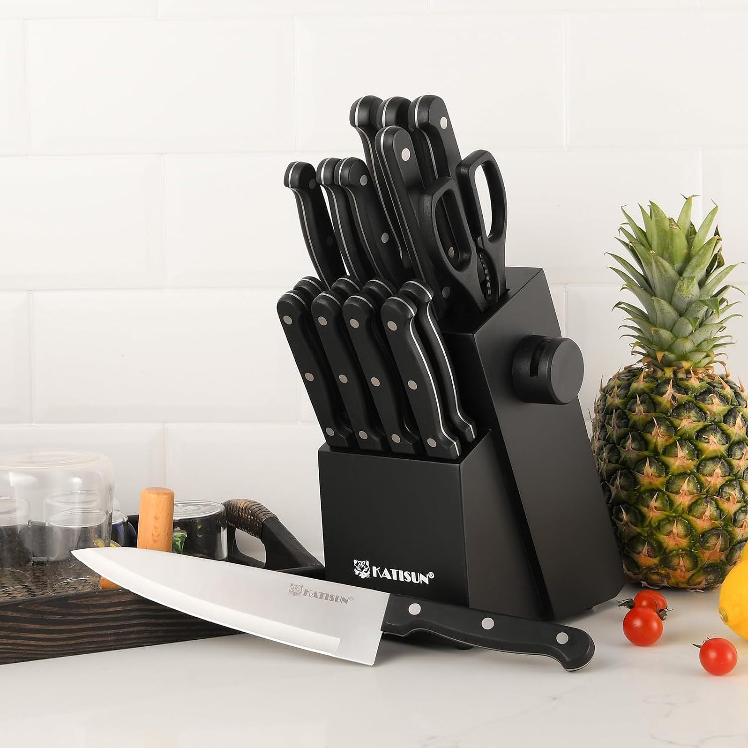 Black knife set with a block on a kitchen counter, featuring a pineapple and vegetables.