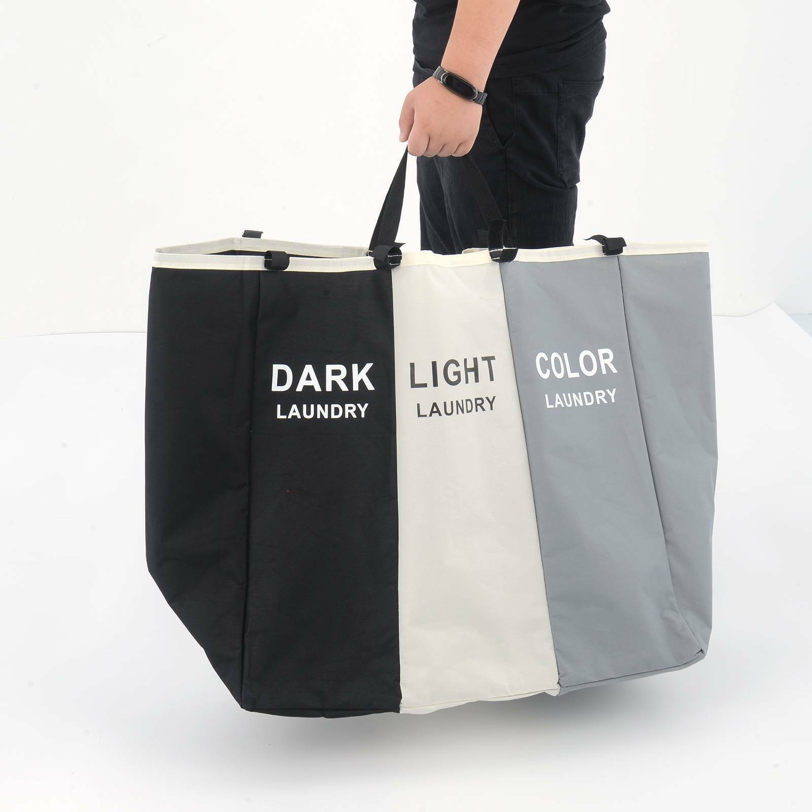 Three-section laundry bag labeled 'Dark Laundry', 'Light Laundry', and 'Color Laundry' held by a person.
