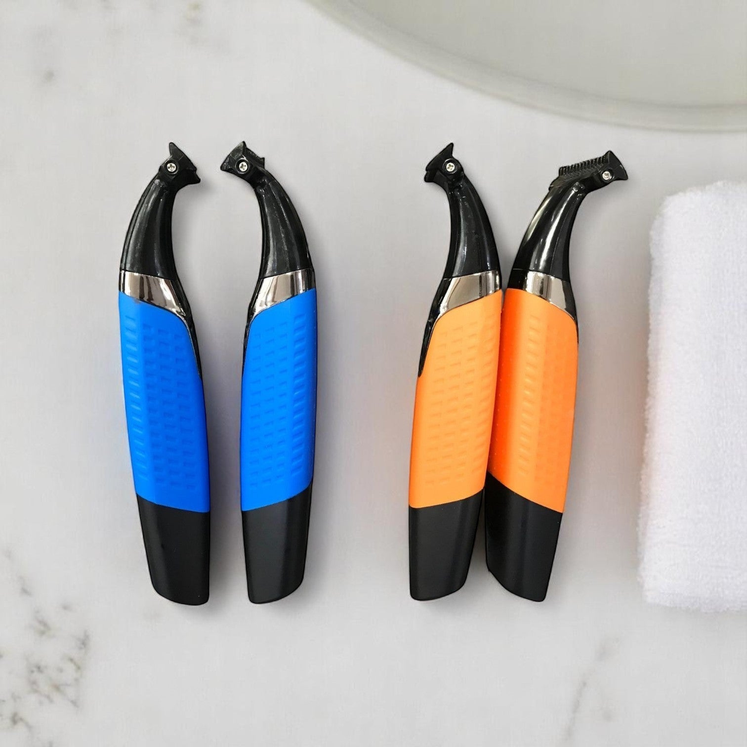 Two blue and two orange electric razors on a marble surface with a white towel.