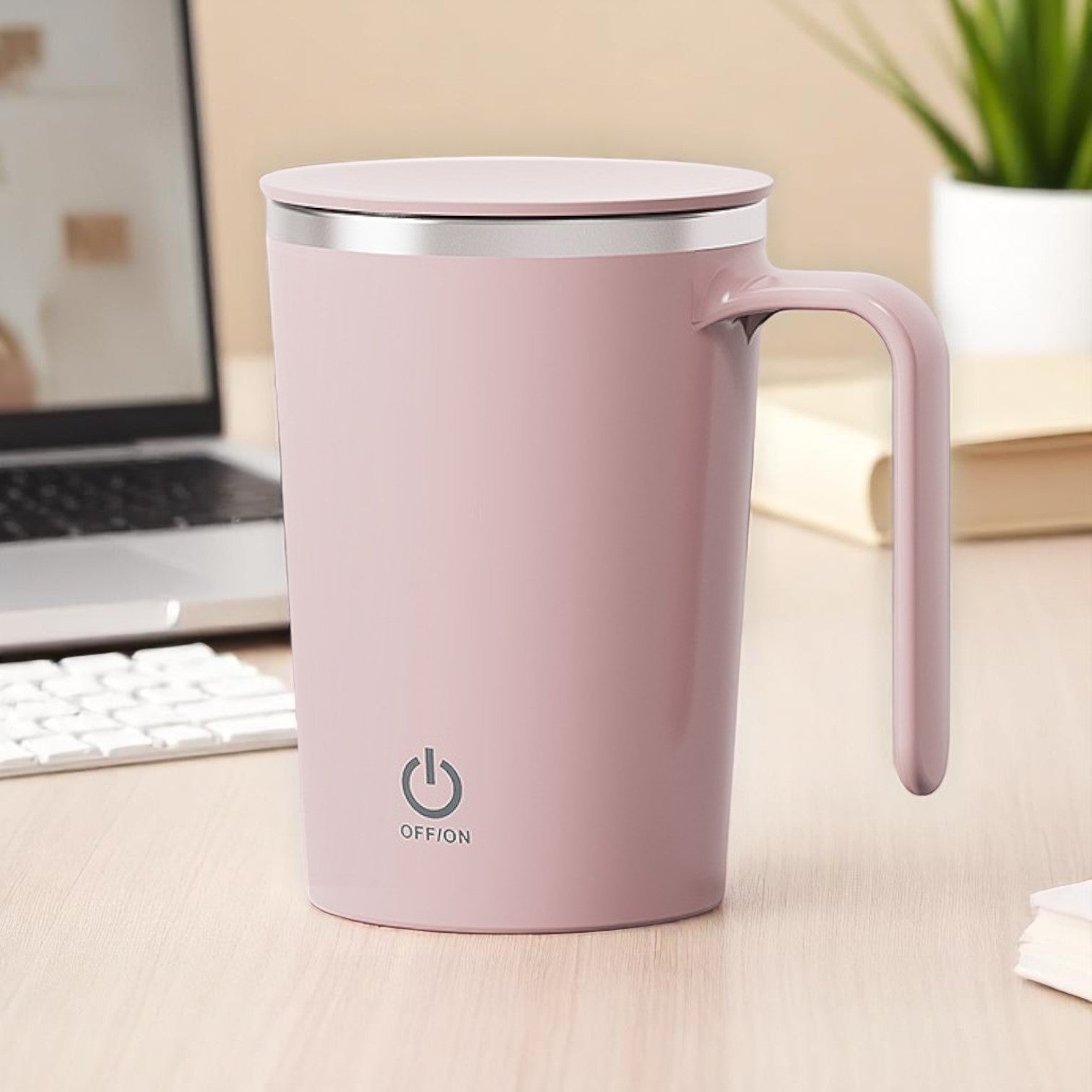 Pink mug with a power symbol on a desk with a laptop and keyboard.