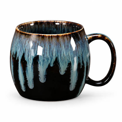 A ceramic mug with a glossy black base and a dripping glaze effect in light blue and dark brown, shown on a white background.