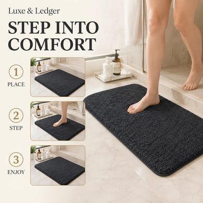 A dark charcoal gray plush bath mat shown in a bathroom scene with a person stepping onto it, alongside three inset diagrams labeled Place, Step, and Enjoy. Text at the top reads 'Luxe & Ledger' and 'STEP INTO COMFORT'.