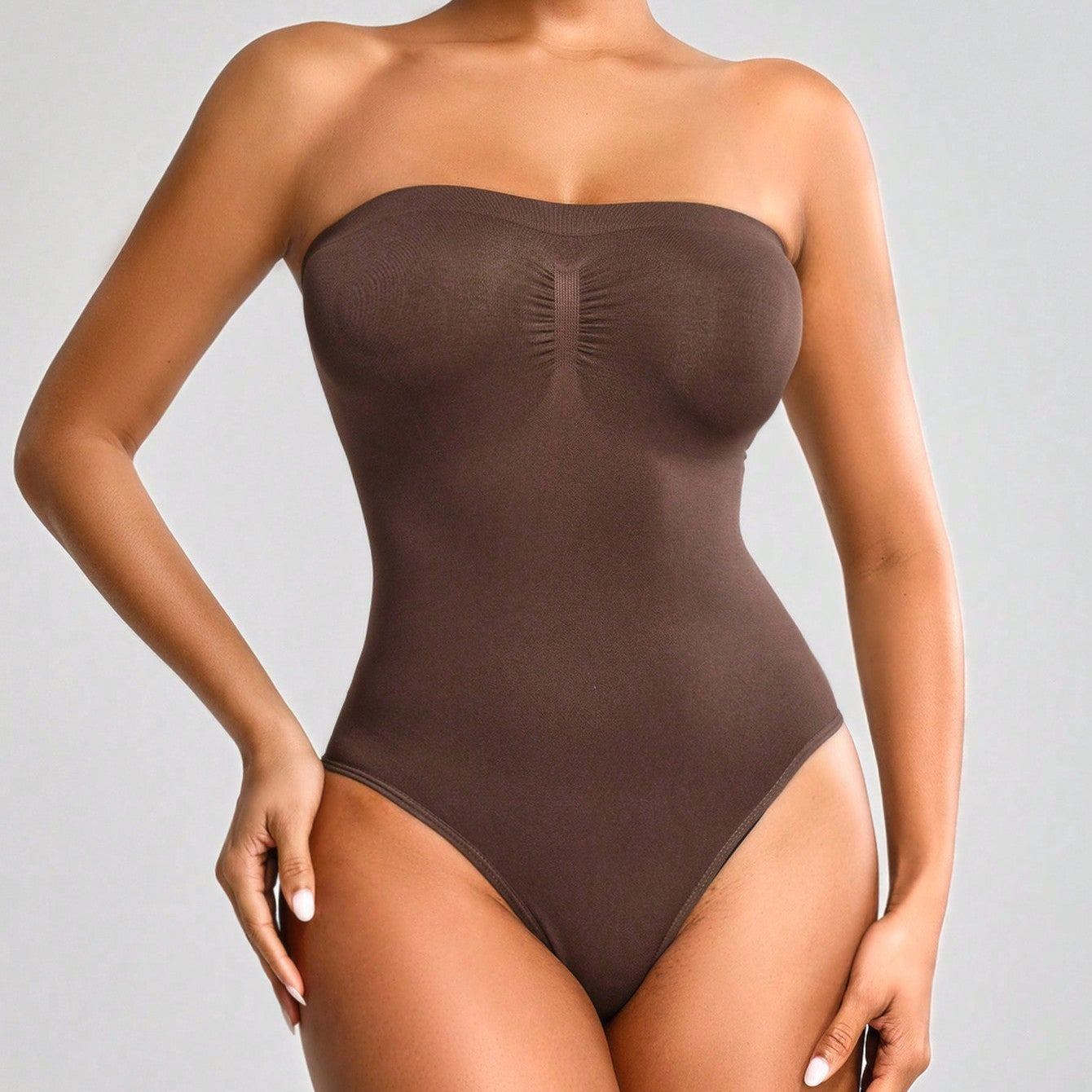 Brown strapless bodysuit worn by a model on a gray background