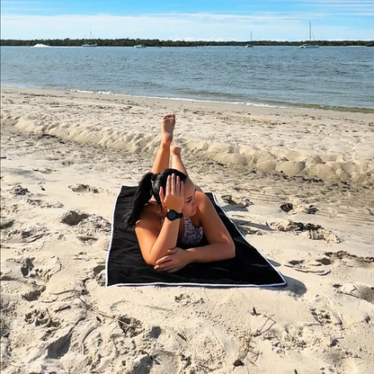 Person lying on a towel at the beach with water and sky in the background