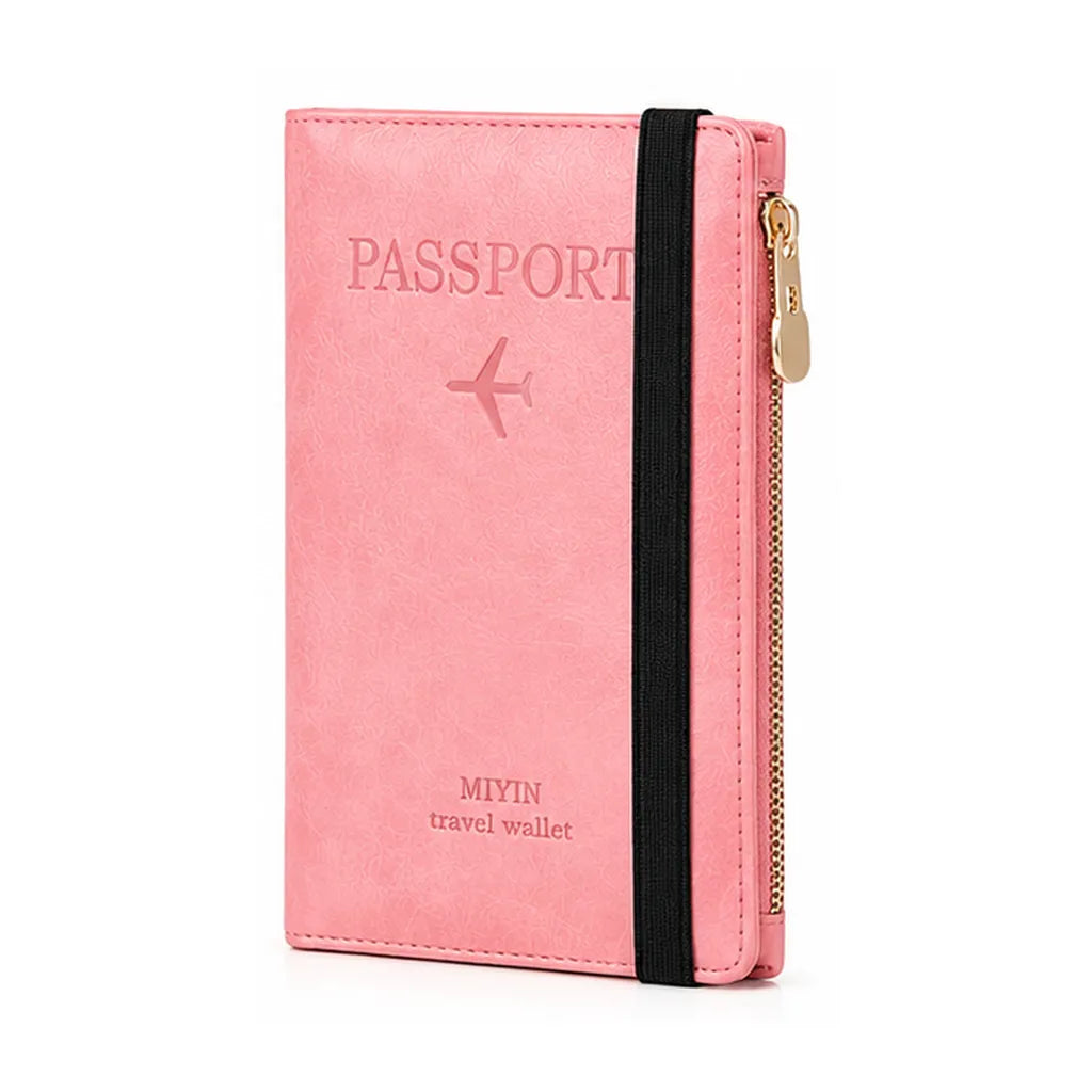 A pink faux-leather passport holder travel wallet with an elastic black band and a gold zipper, featuring an embossed passport design on the front.