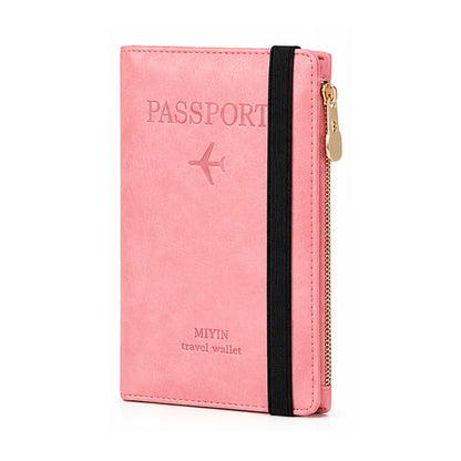 A pink faux-leather passport holder travel wallet with an elastic black band and a gold zipper, featuring an embossed passport design on the front.