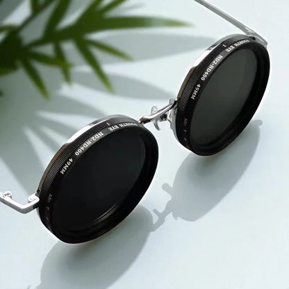 Round sunglasses with reflective lenses on a light surface with a plant in the corner