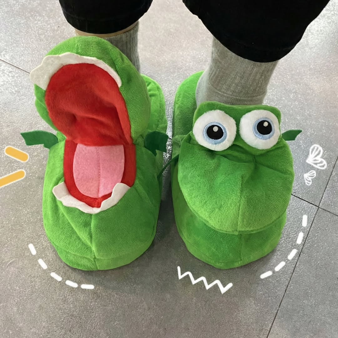 Green cartoonish slippers with a mouth and eyes on a tiled floor.