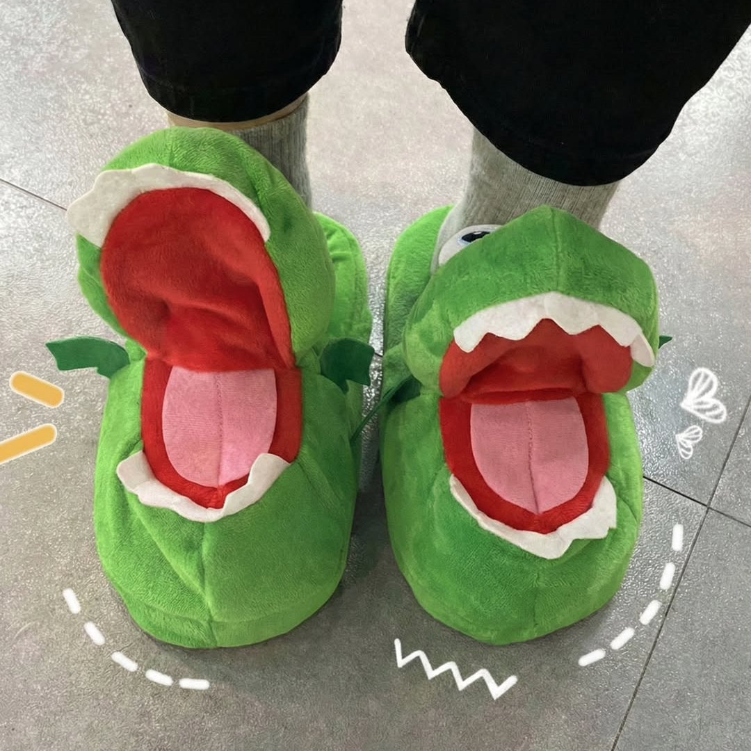 Green dinosaur-shaped slippers worn indoors on a tiled floor.