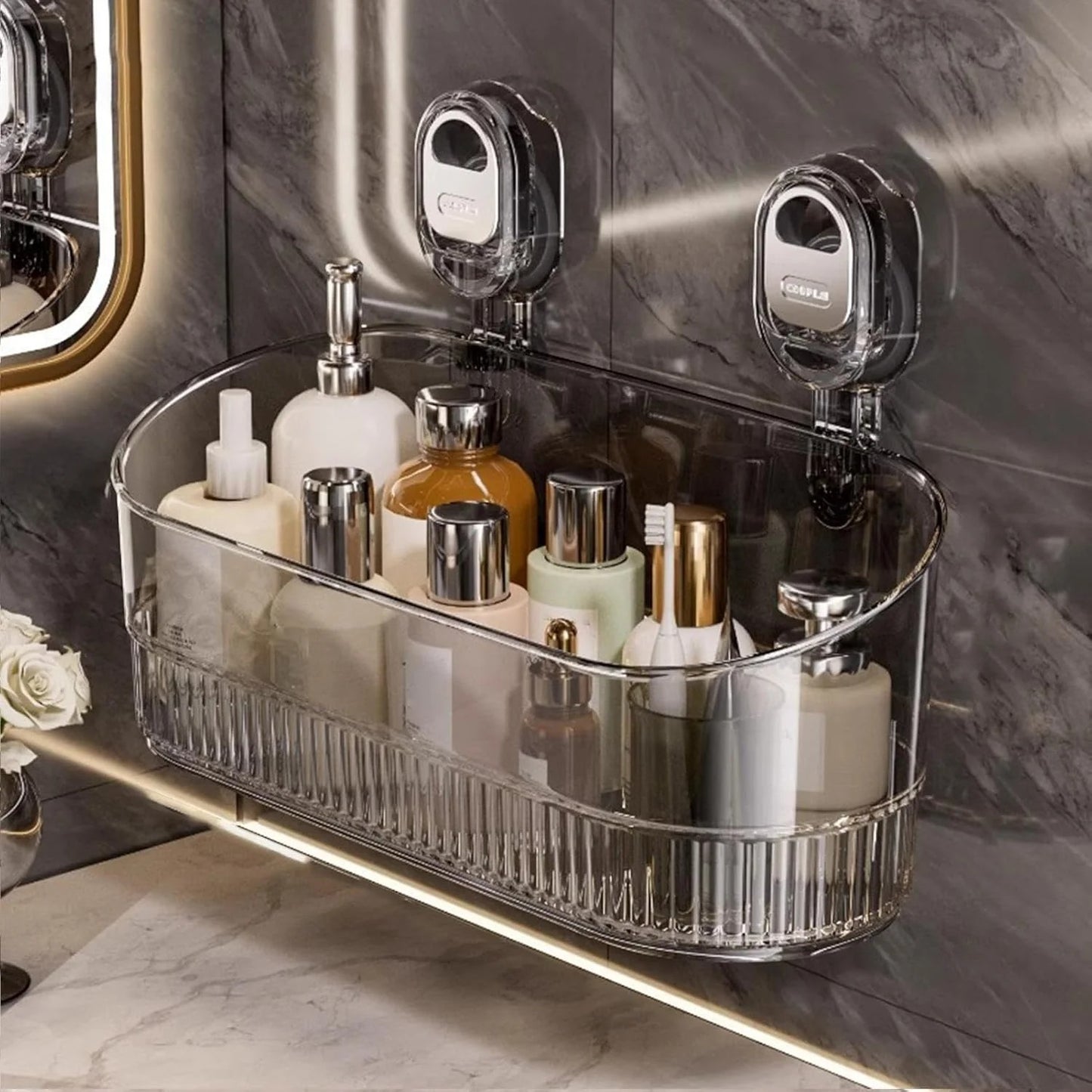 Clear bathroom caddy with toiletries on a marble shelf against a marble wall.