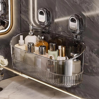 Clear bathroom caddy with toiletries on a marble shelf against a marble wall.