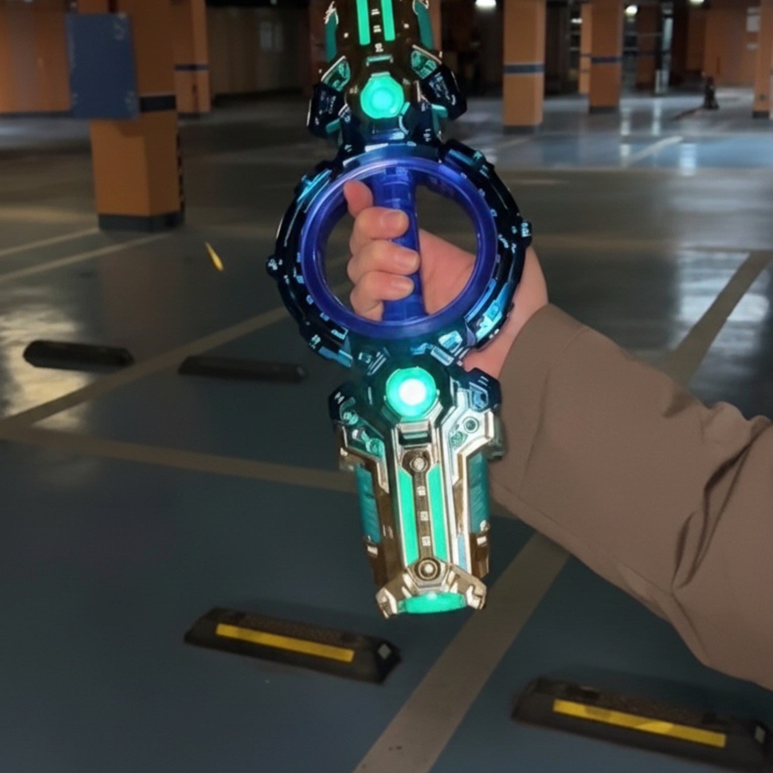 Hand holding a futuristic blue and green weapon in an indoor setting