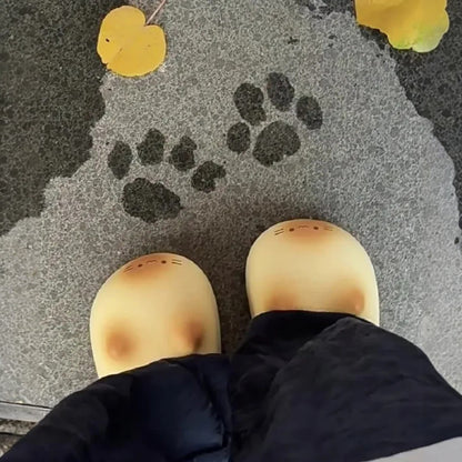Paw prints on a textured surface with a person wearing yellow shoes and black pants.