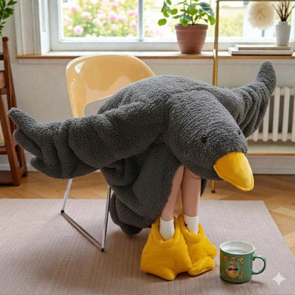 Person wrapped in a gray blanket with a yellow duck-shaped hood in a cozy room.