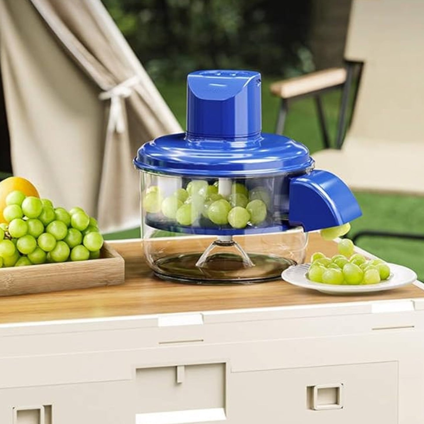 Blue juicer with green grapes on a wooden table outdoors