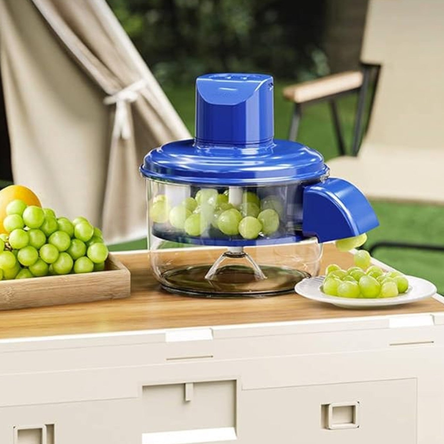 Blue juicer with green grapes on a wooden table outdoors
