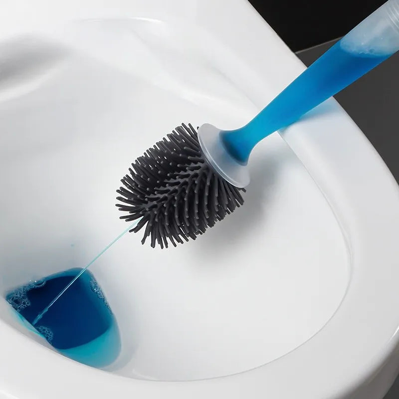 Cleaning brush with blue liquid being used to clean a toilet bowl.