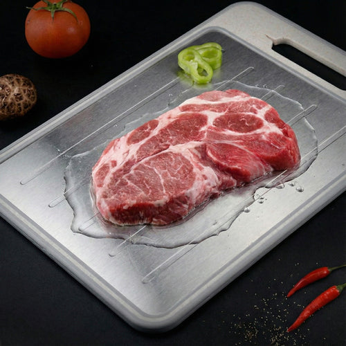 Raw steak on a metal tray with vegetables on a dark background
