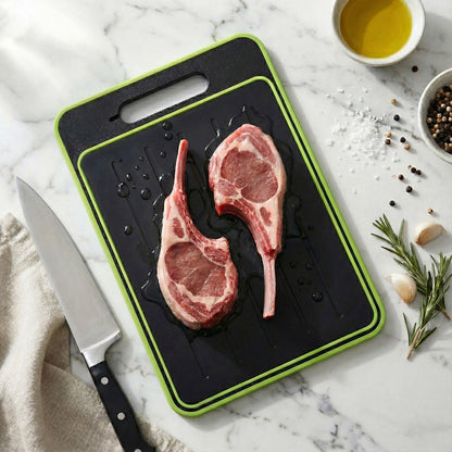 Two raw lamb chops on a black cutting board with a knife, oil, and spices on a marble surface.