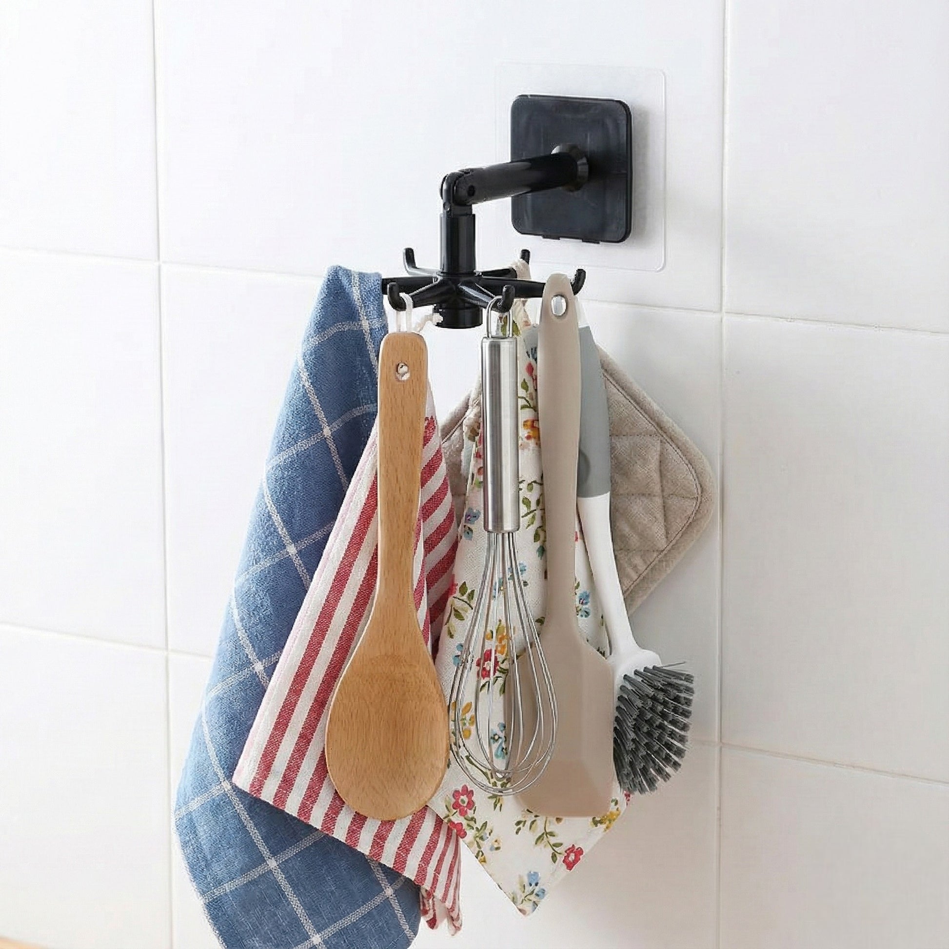 Kitchen utensils hanging on a wall-mounted hook with a white tiled background