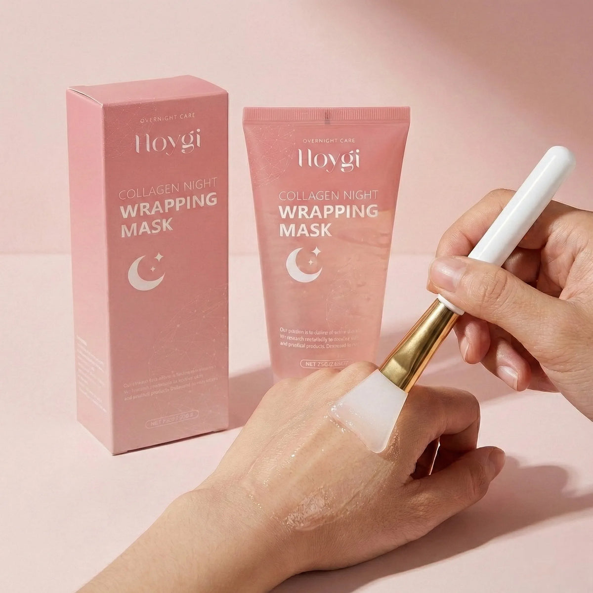 Hoygi Collagen Night Wrapping Mask shown with its pink box and tube packaging, alongside a hand applying the mask with a white-handled brush.