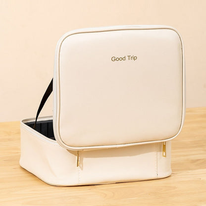 Beige toiletry bag with 'Good Trip' text on a wooden surface
