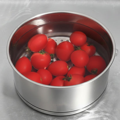 Red tomatoes in a metal steamer basket on a gray background