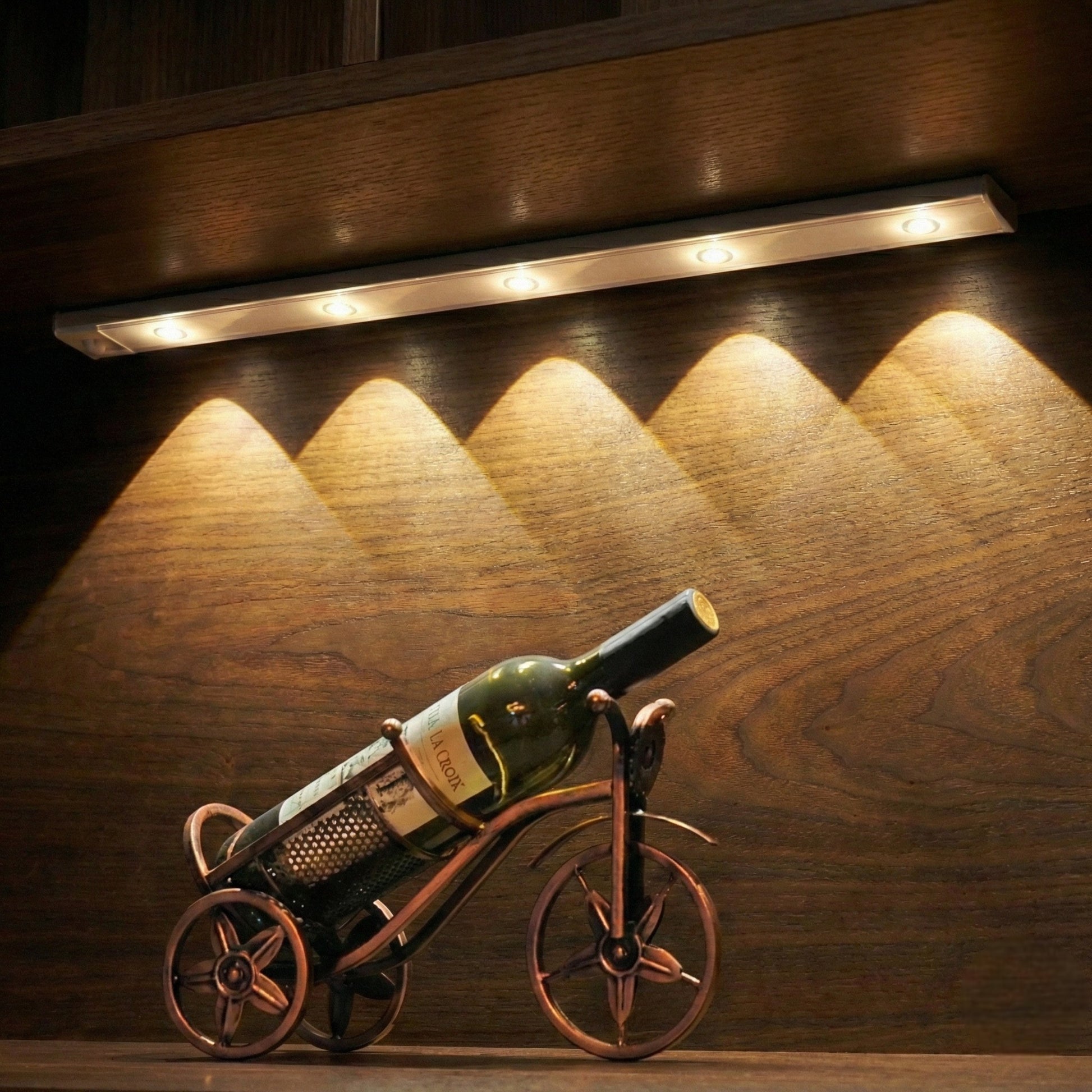 Wine bottle on a decorative bicycle stand with warm lighting on a wooden surface