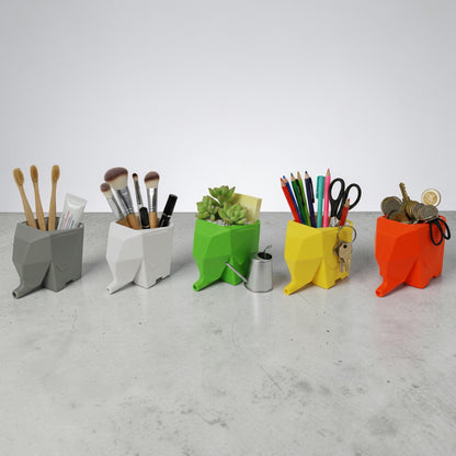 Five colorful geometric desk organizers on a gray surface with various items inside.