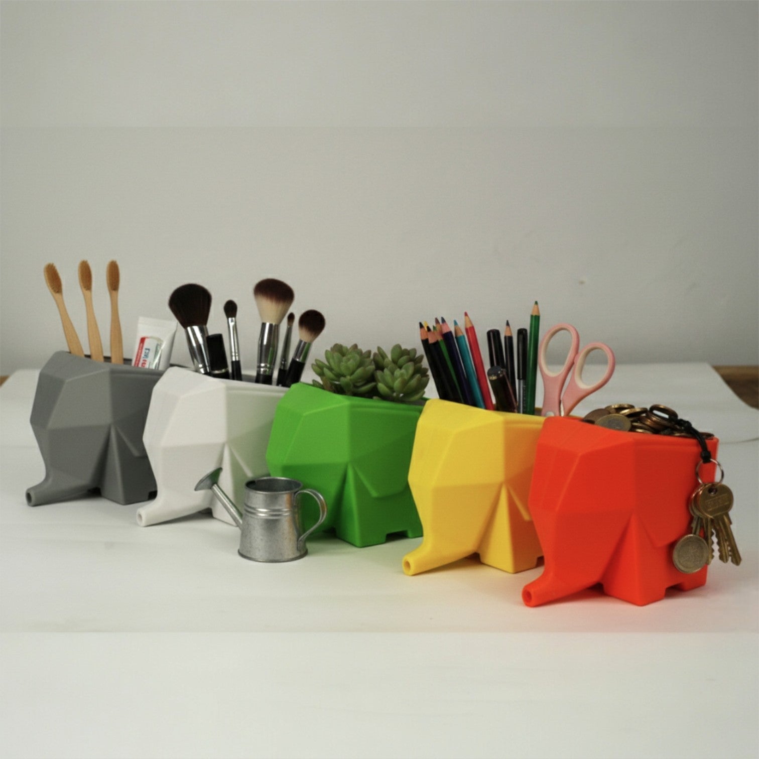 Colorful elephant-shaped desk organizers with stationery items on a white surface.